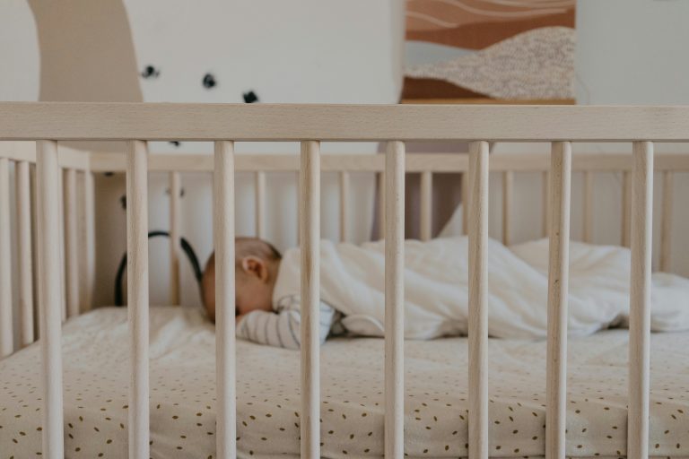 Baby sleeping in a crib with a soft mattress and cozy blanket, representing a peaceful scene ideal for parents using the best baby monitor.