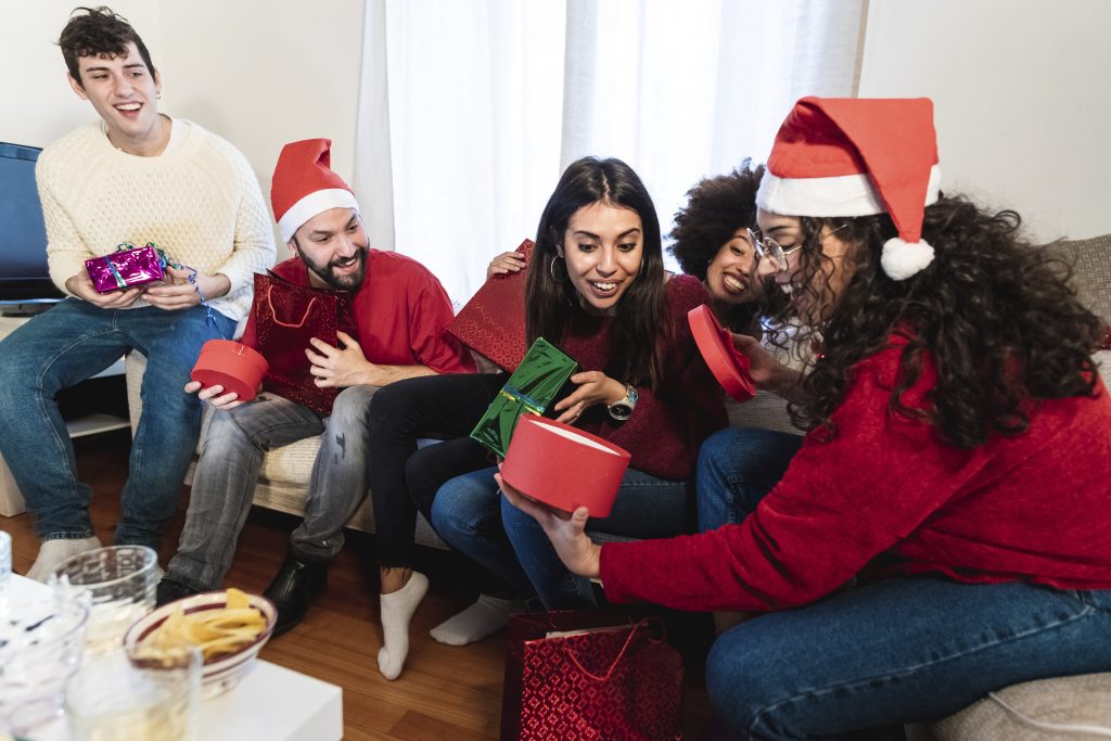 Friends sharing gifts and laughter in a cozy Christmas gathering