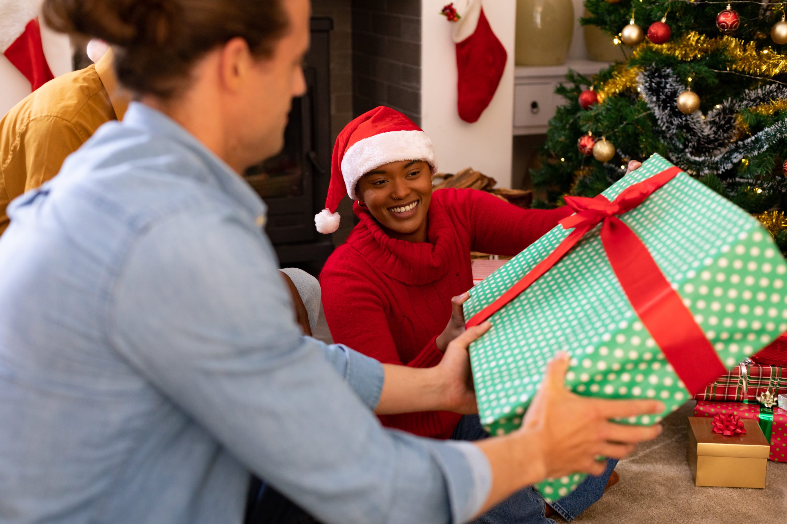 Happy diverse female and male friends sharing presents at christmas time. christmas festivities, celebrating at home with friends.