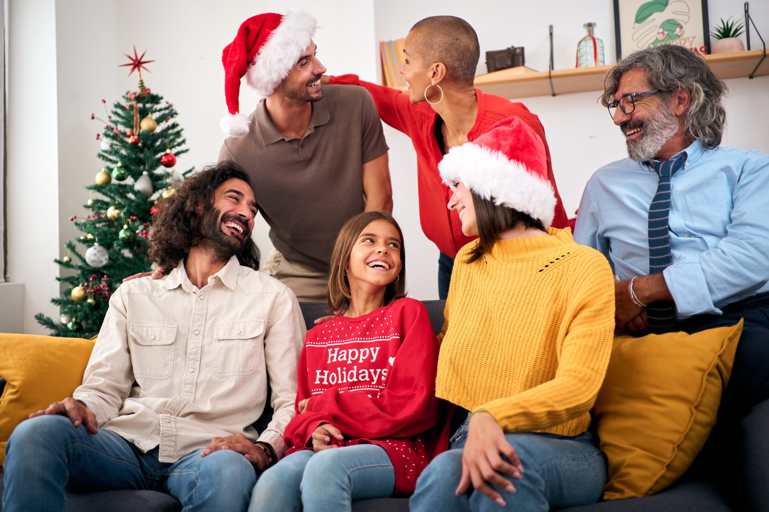 Joyful family Christmas gathering sitting on sofa in living room at home. Three Caucasian generations making holiday domestic life. Happy people together on eve advent and friendly relations indoor.