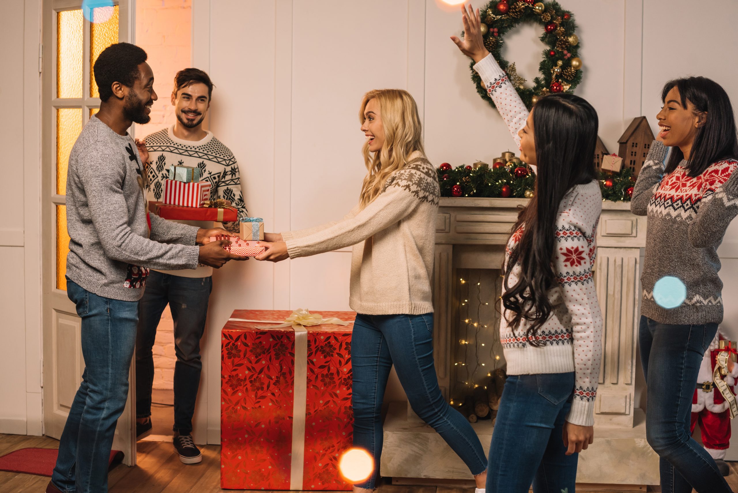 multicultural men presenting christmas gifts to friends while celebrating gifts together