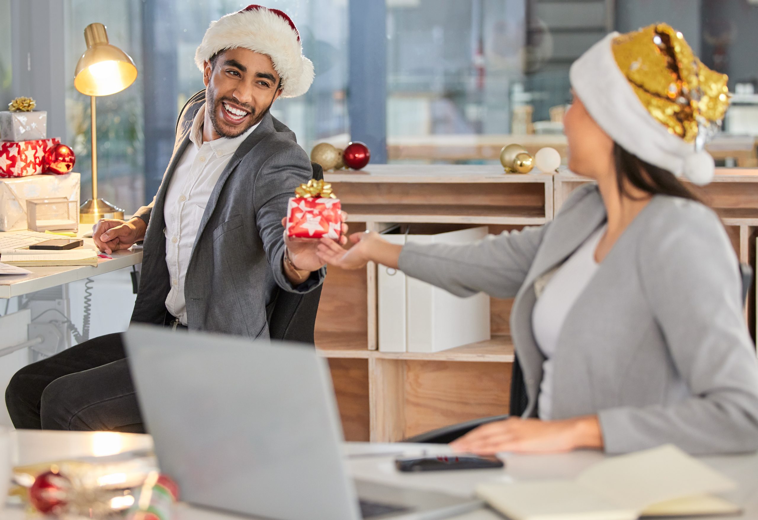 Shot of a young businessman and businesswoman exchanging Christmas gifts in a modern office.