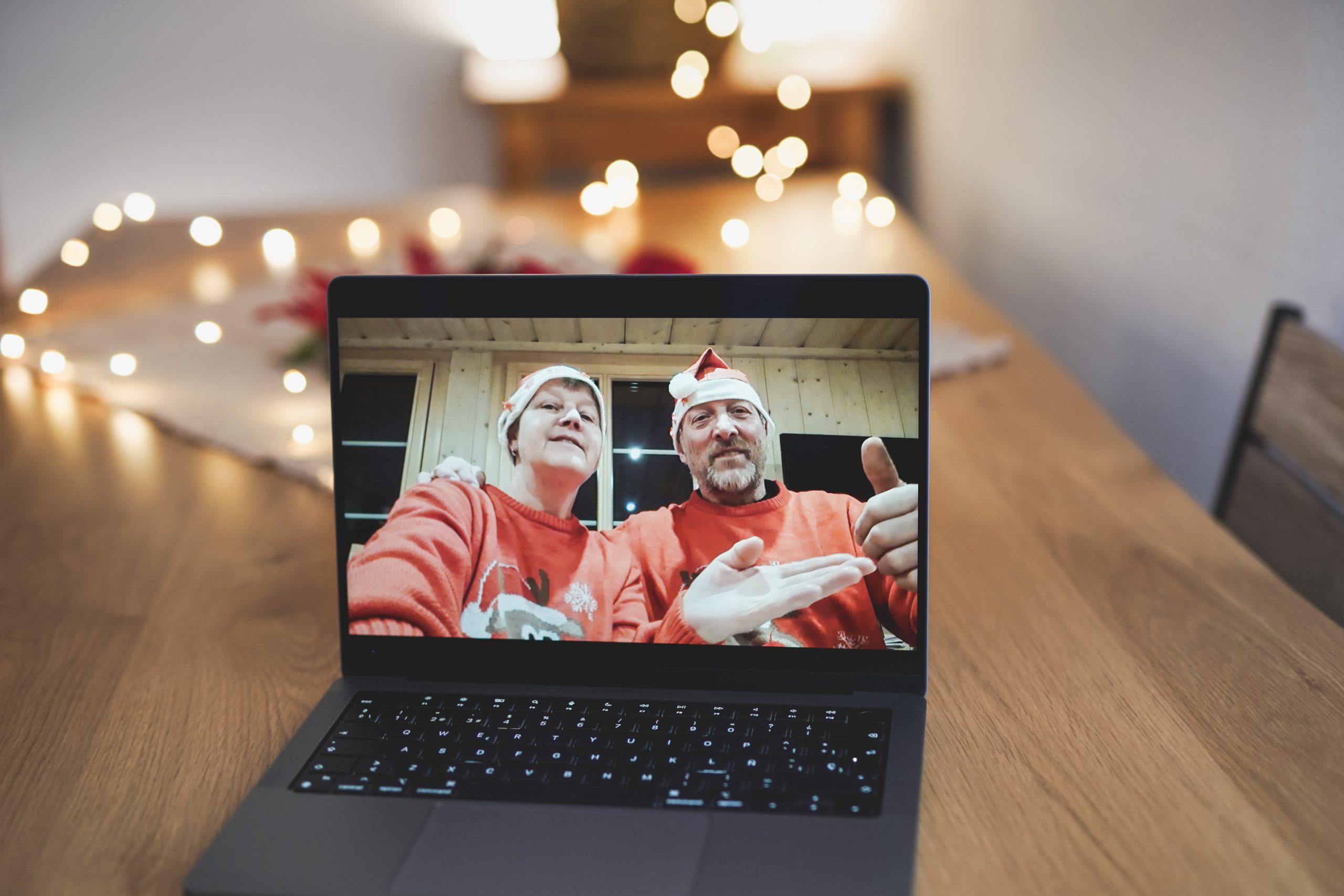 Video call on laptop screen with senior couple wearing christmas hat