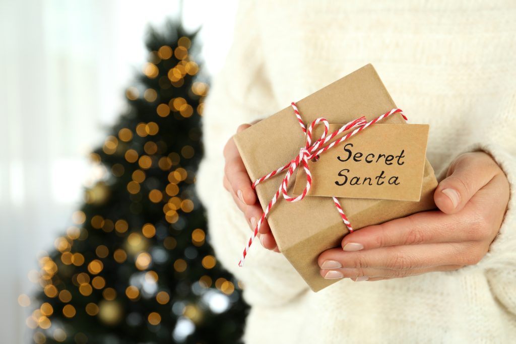 Woman holds Secret Santa gift box, close up
