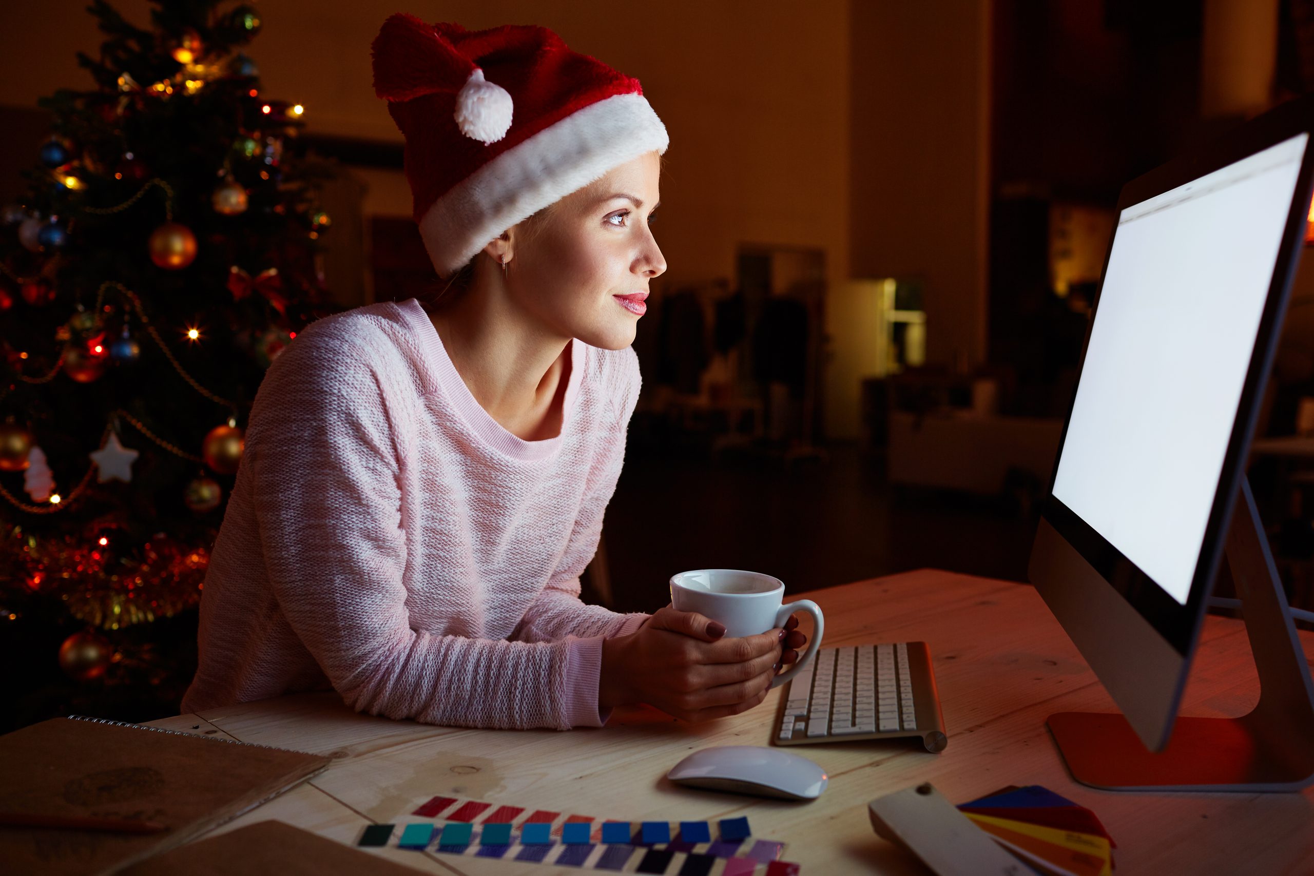 Woman in Santa cap networking on xmas night