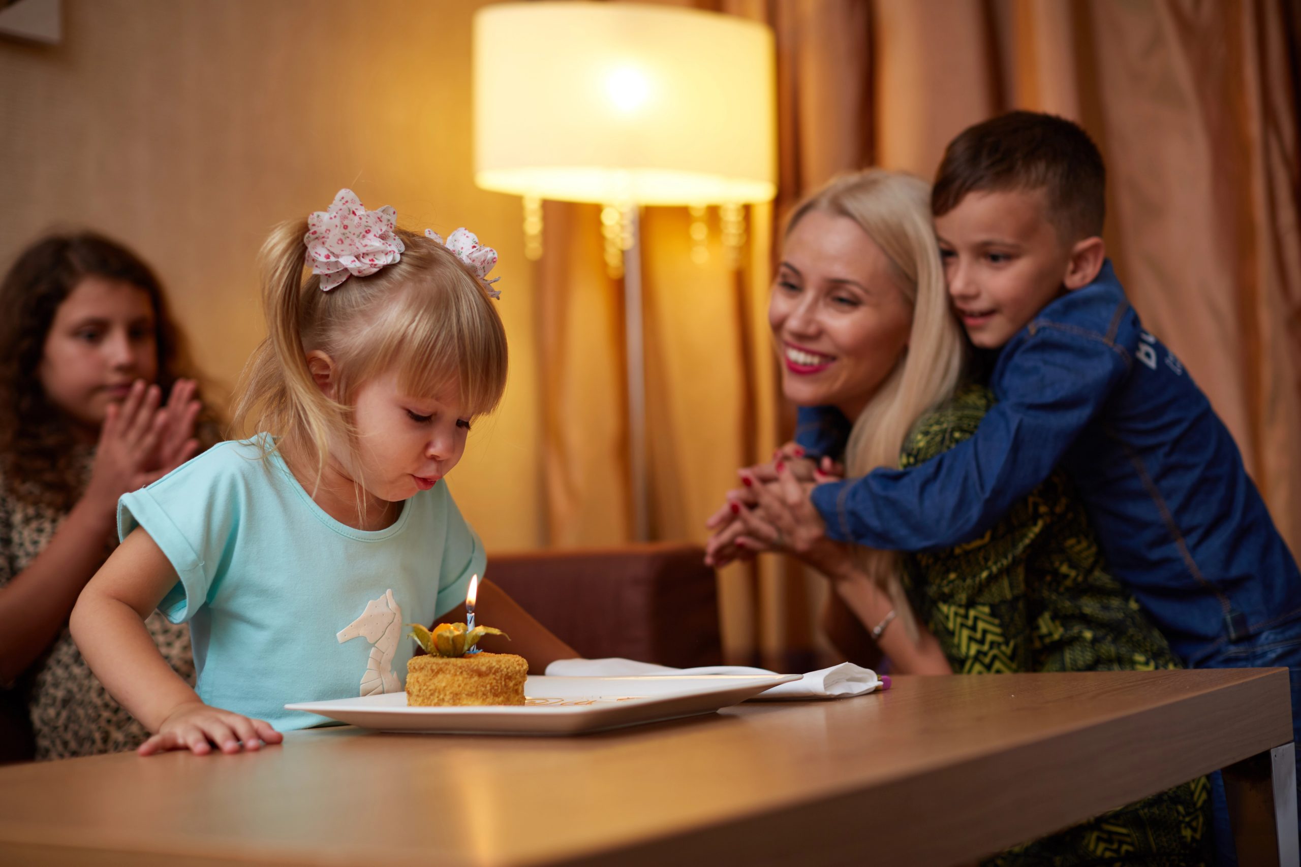 girl blowing candle out on cupcake