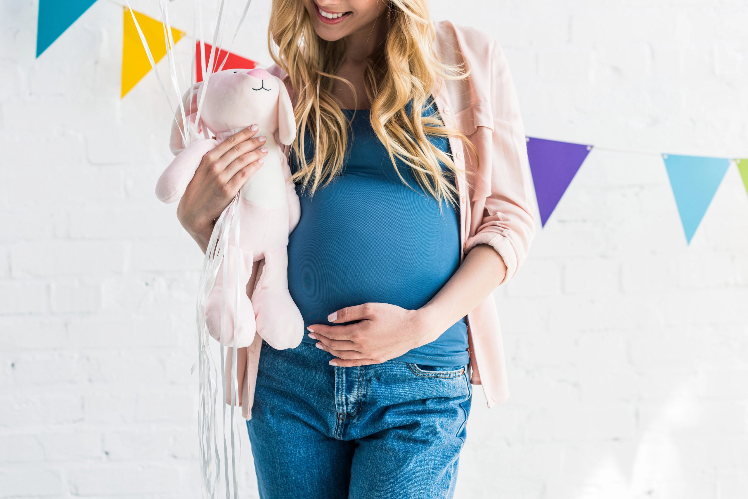 pregnant woman holding pink stuffed plush bunny