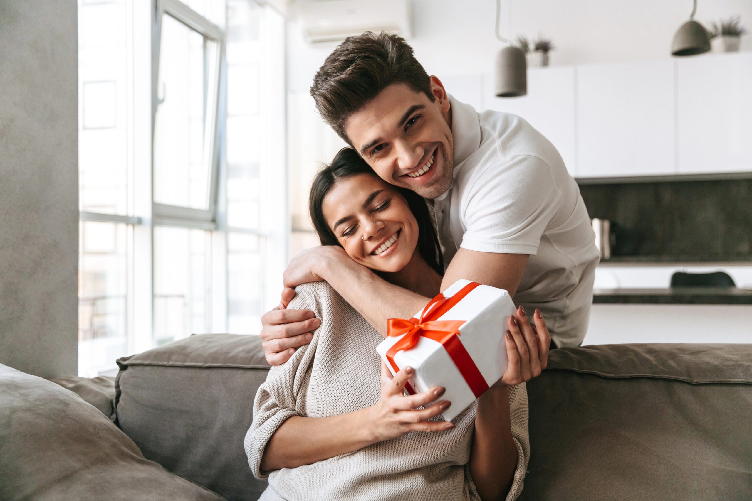 Boyfriend hugging girlfriend while she holds present