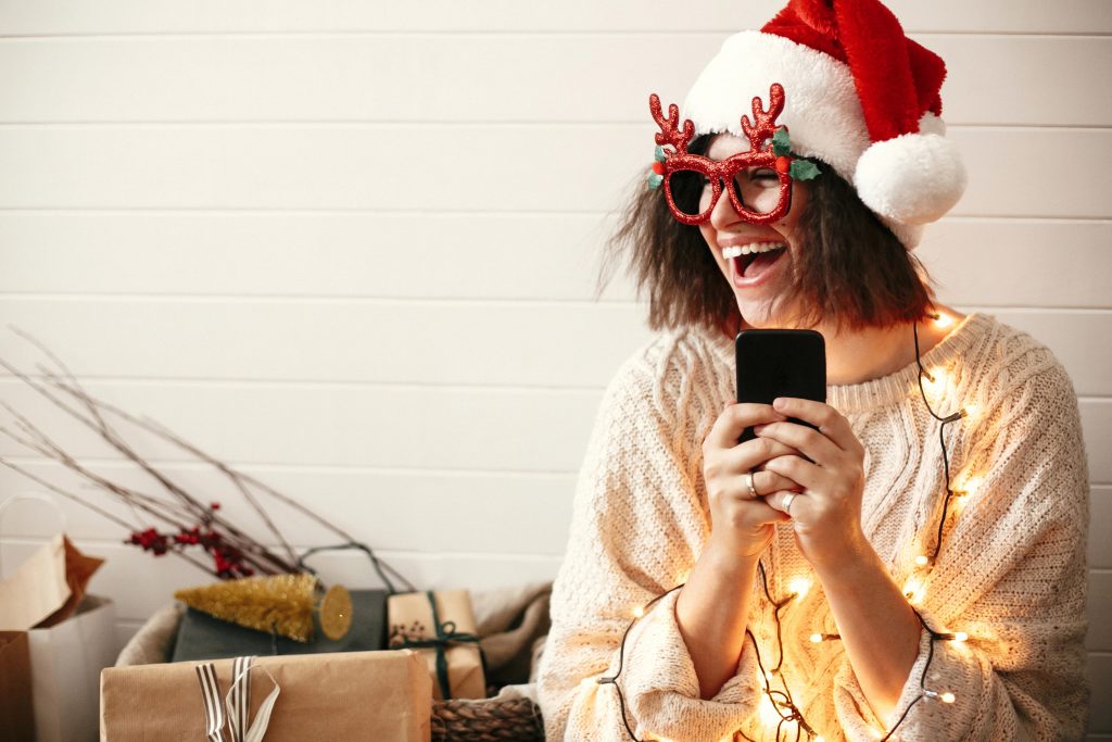 woman laughing at christmas meme on phone