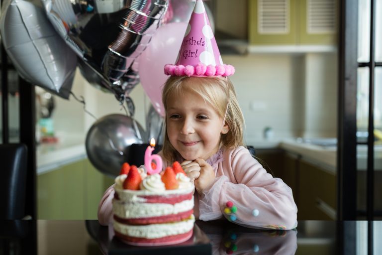 Little girl next to birthday cake