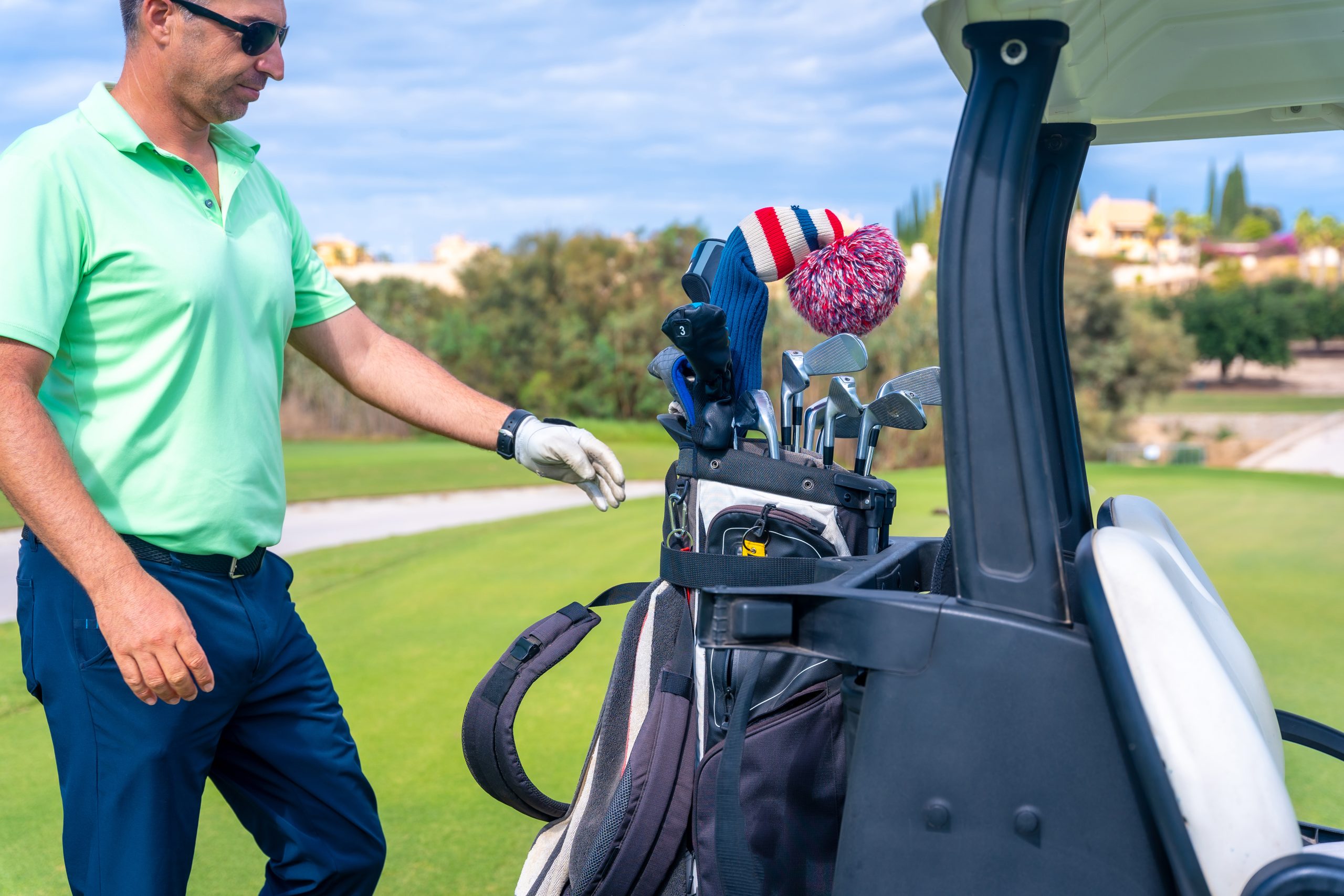 Man in the golf cart with the bag of clubs playing golf, golf club