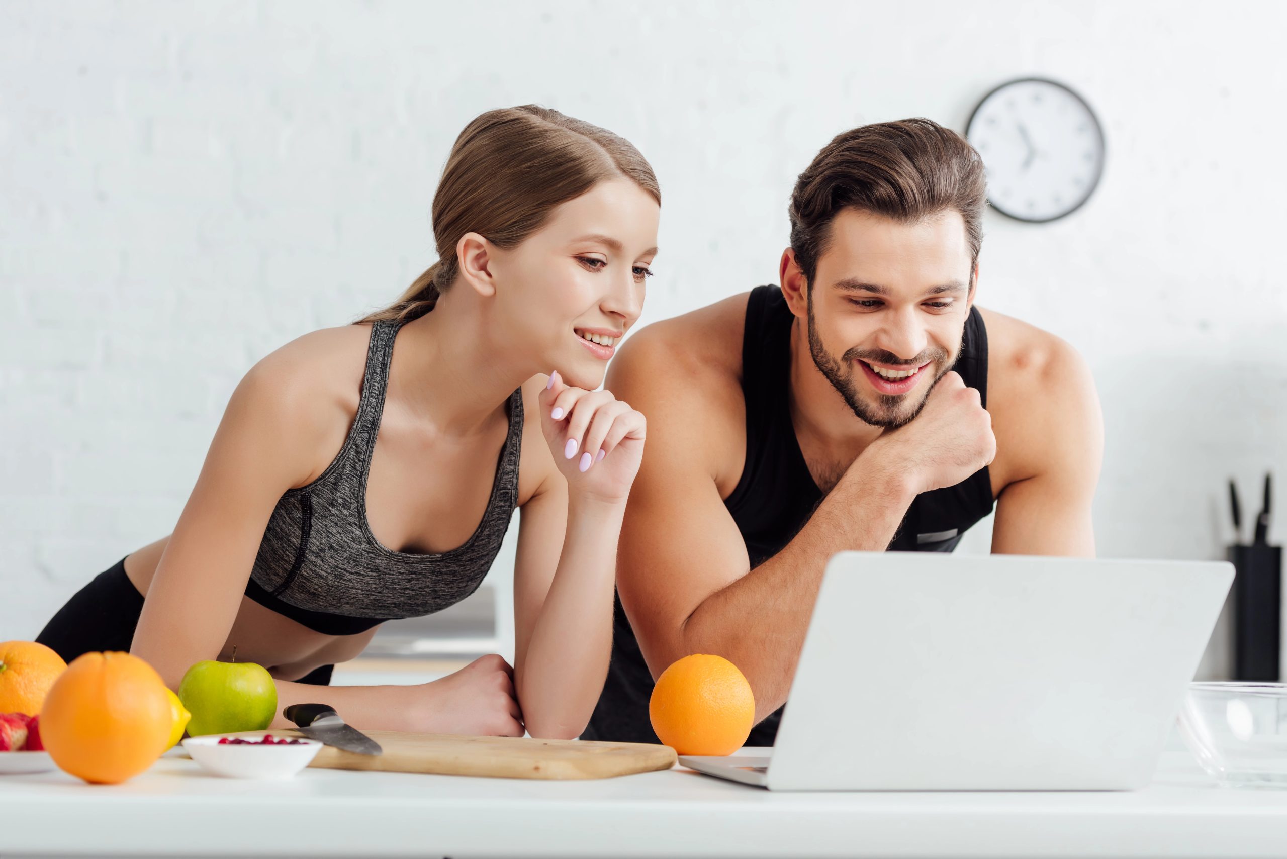 man and woman in fitness gear smiling on computer together