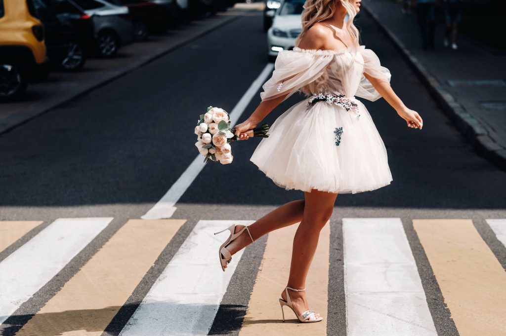 bride crossing street in short wedding dress
