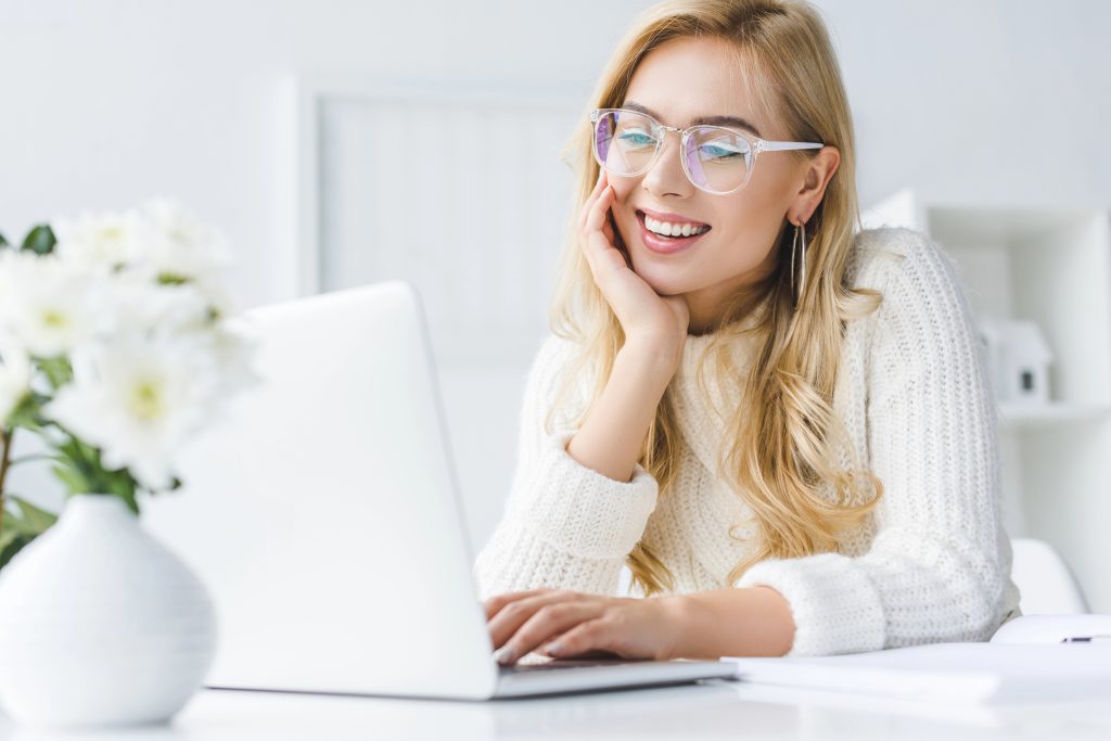 young woman smiling making gift wish list on computer