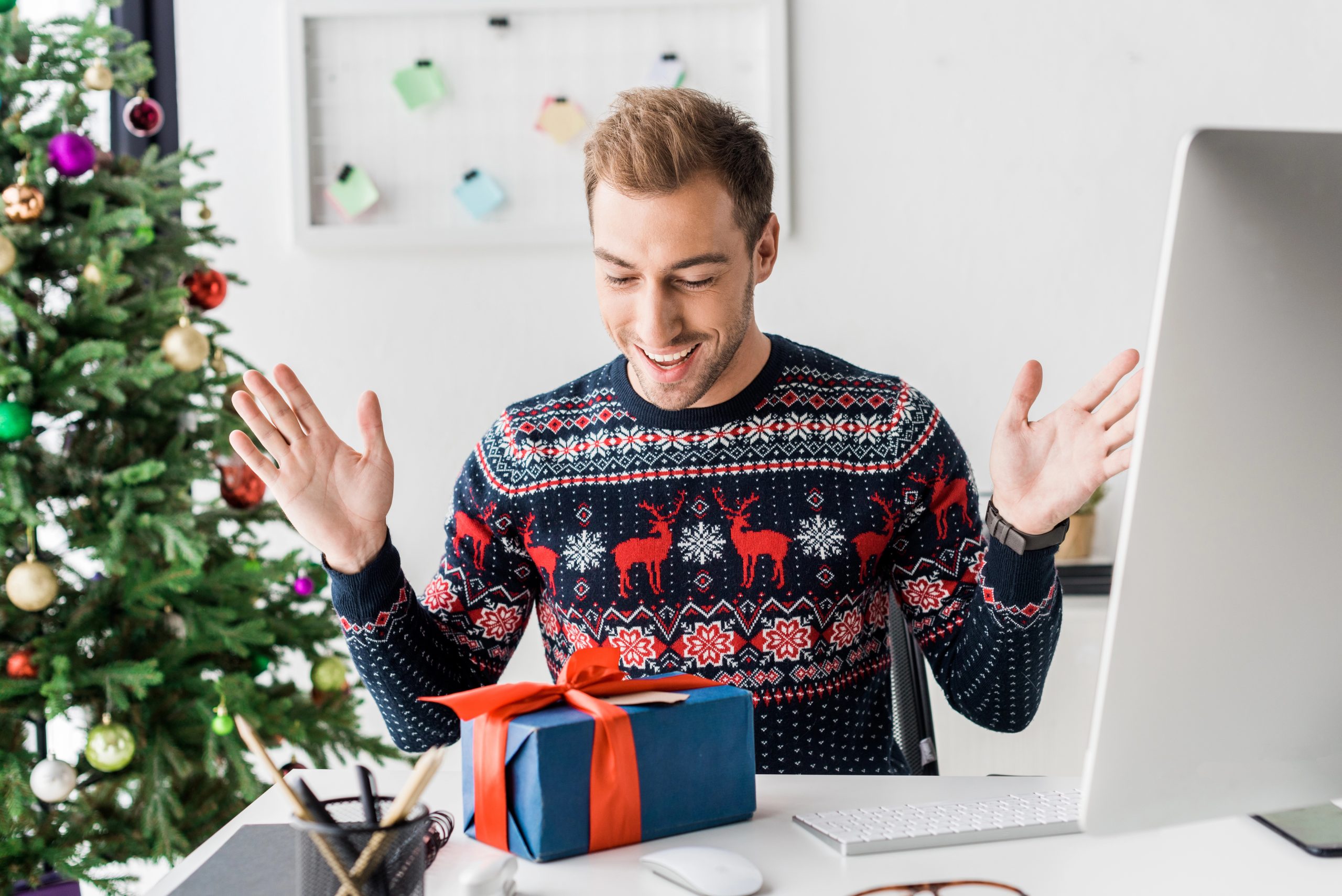man surprised opening gift on computer video call