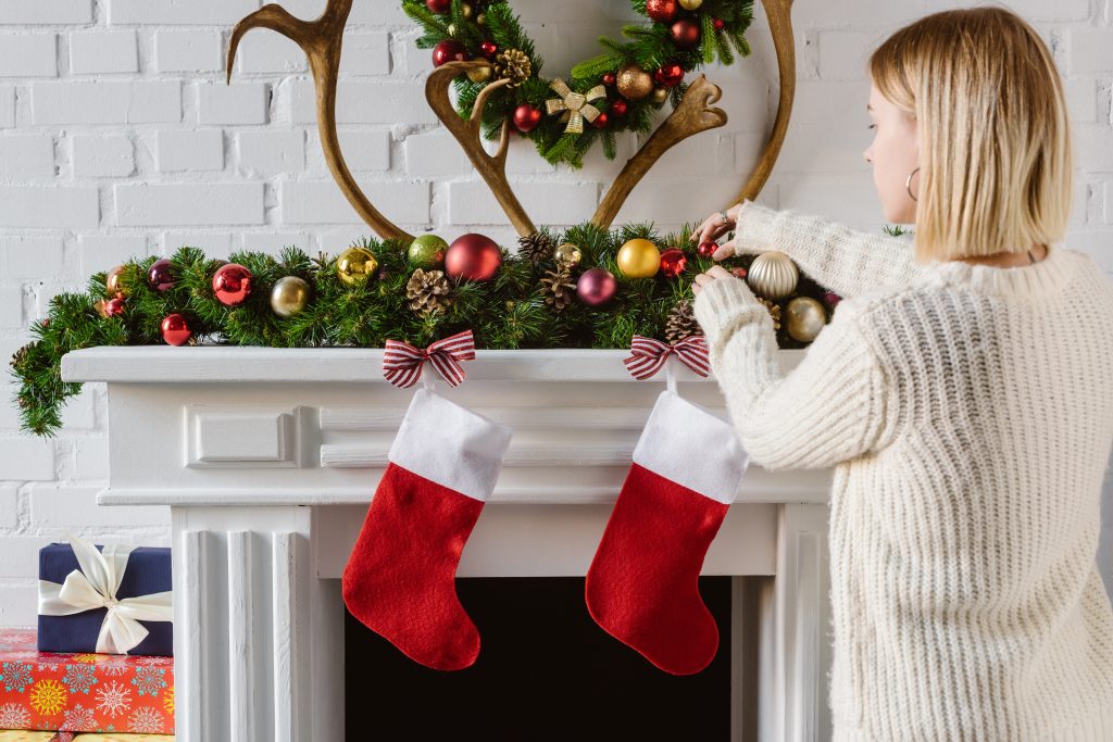 woman adding gifts to christmas stockings