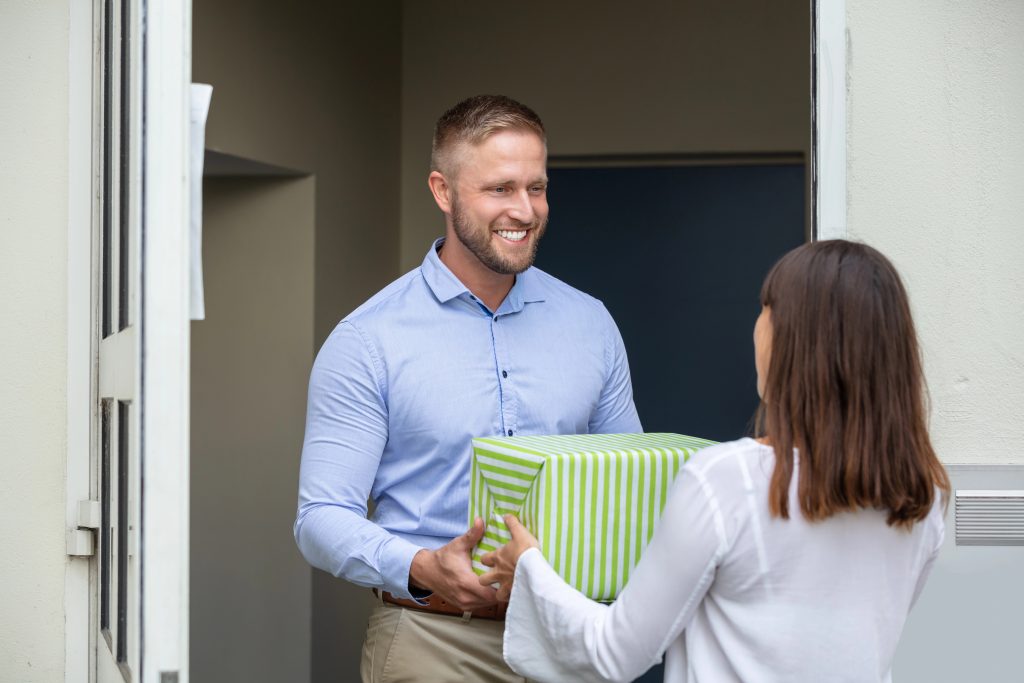 woman giving male neighbor a gift box