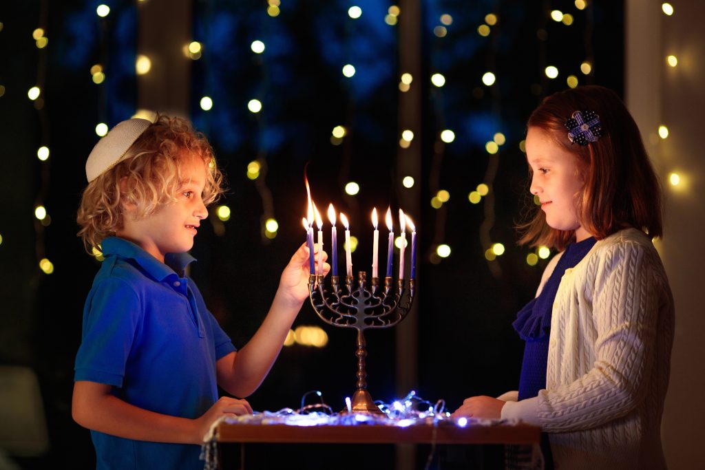 young boy and girl lighting hannukah candles