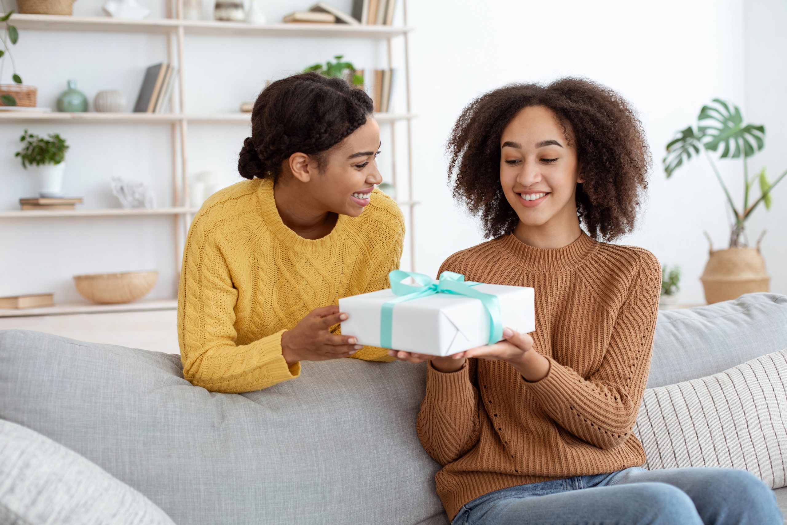 woman giving sister a gift at home