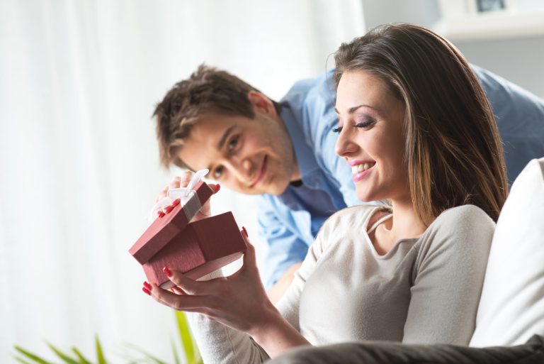 woman opening christmas gift from husband smiling