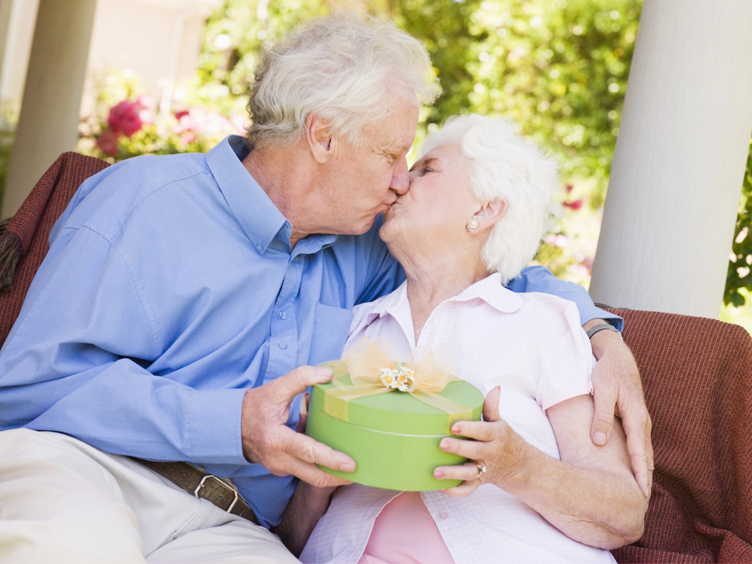 elderly couple kissing when giving gift