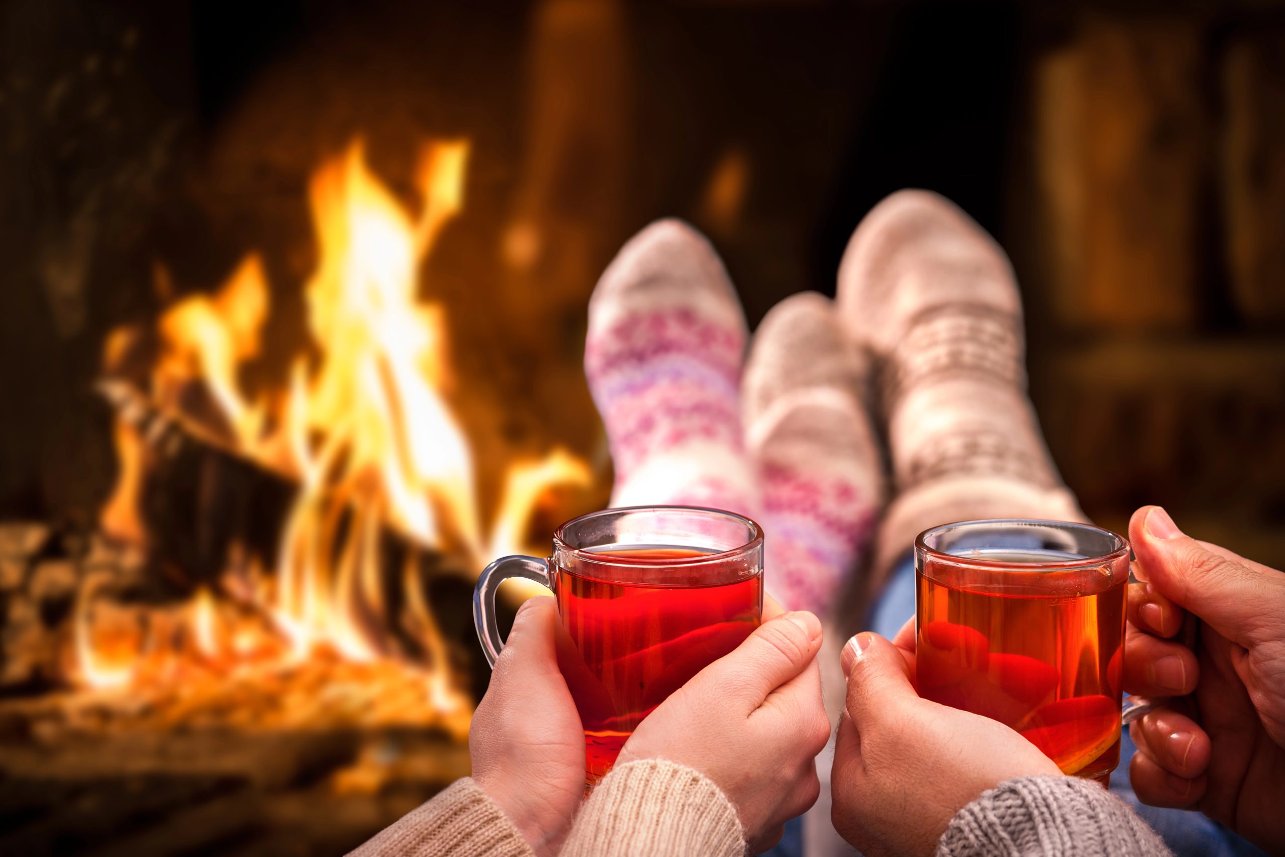 cozy couple by fireplace with tea at christmas