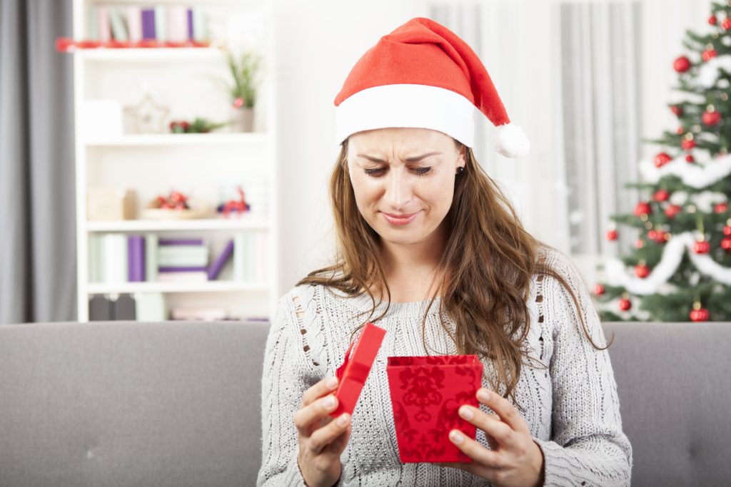 confused woman opening odd christmas gift