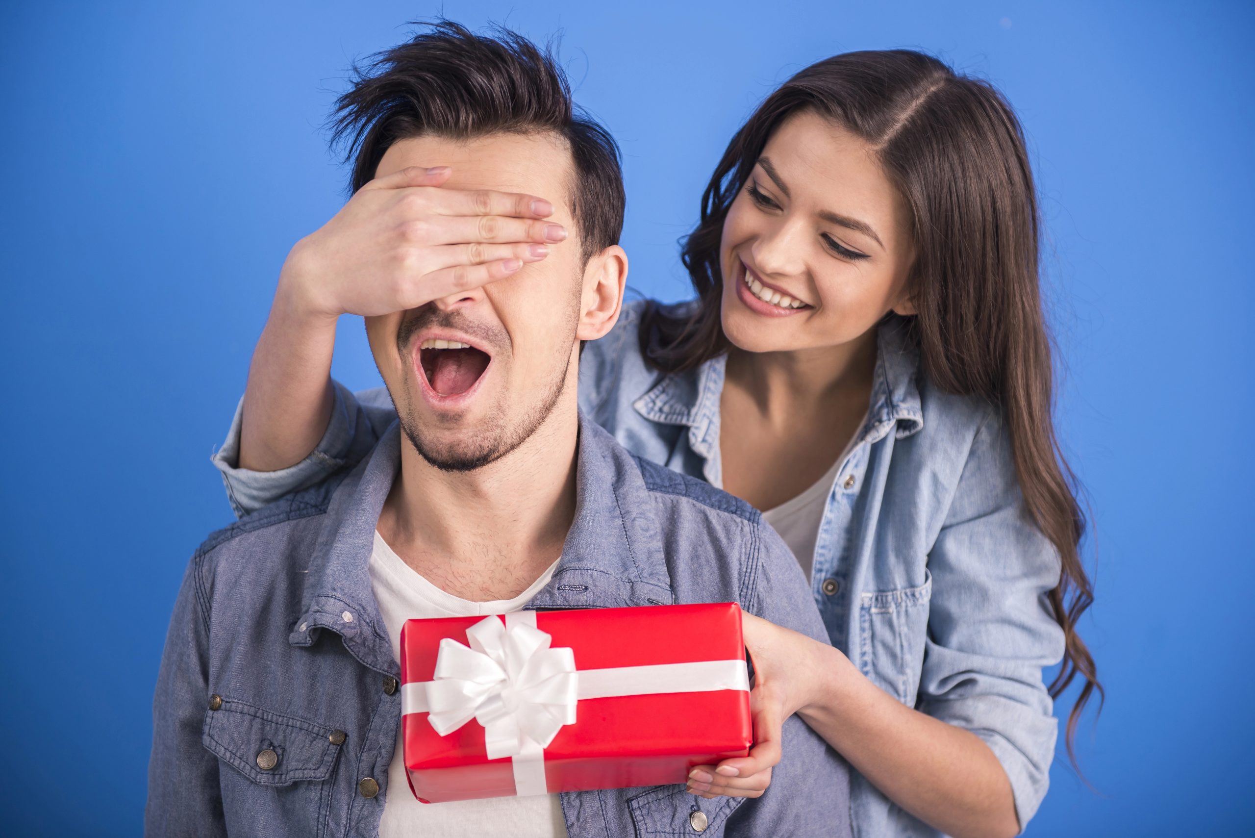 woman surprising man with red gift