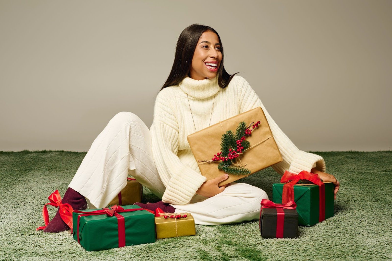 woman in white sweater opening christmas gift