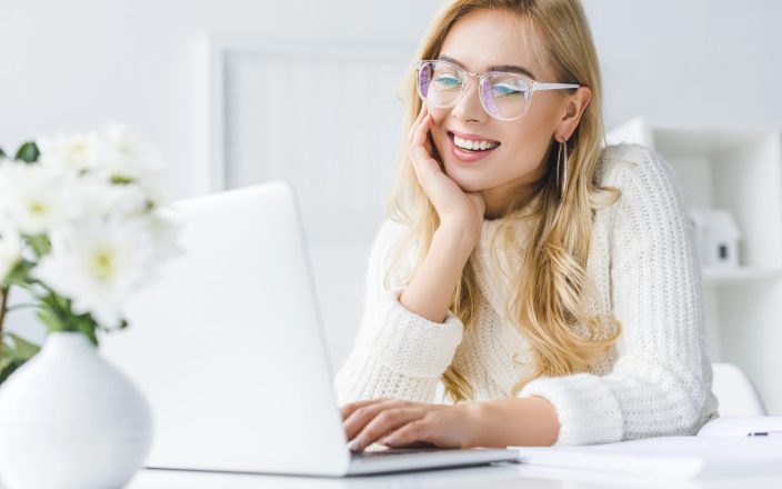 young woman smiling making gift wish list on computer