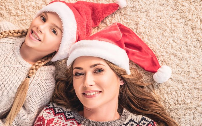 Mom and daughter smiling together with santa hats on