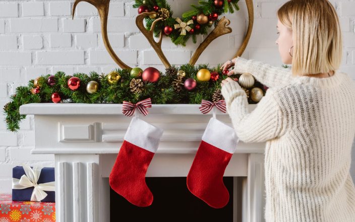 woman adding gifts to christmas stockings