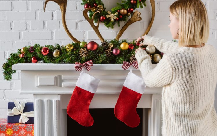 woman adding gifts to christmas stockings