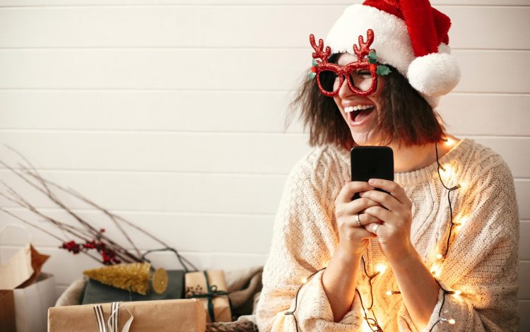 woman laughing at christmas meme on phone