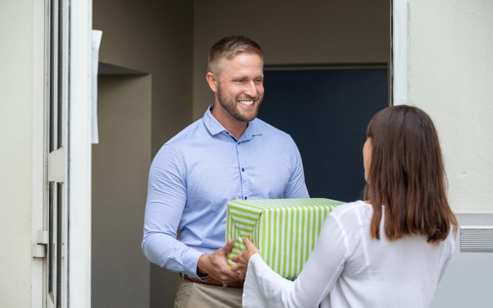 woman giving male neighbor a gift box
