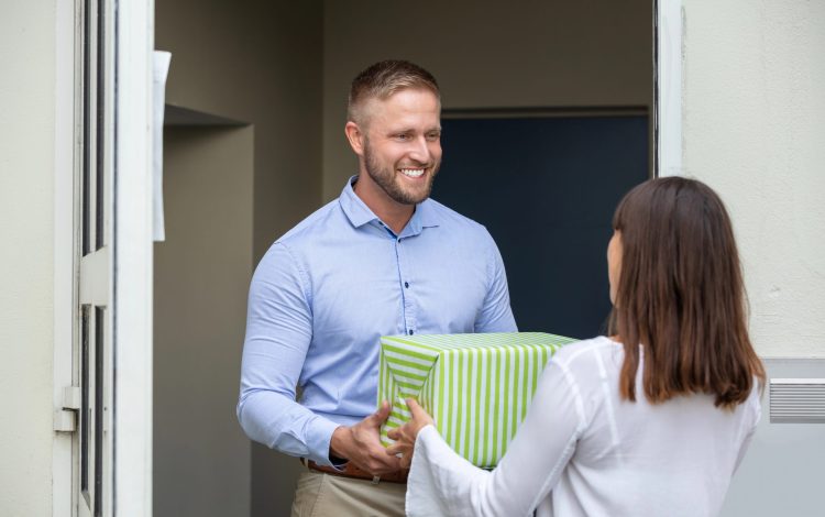 woman giving male neighbor a gift box