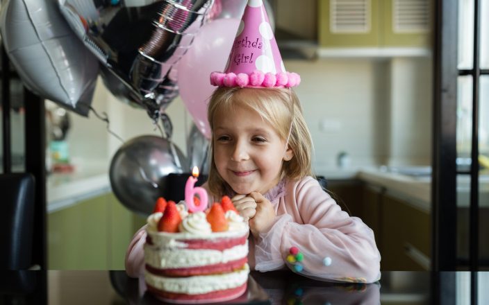 Little girl next to birthday cake