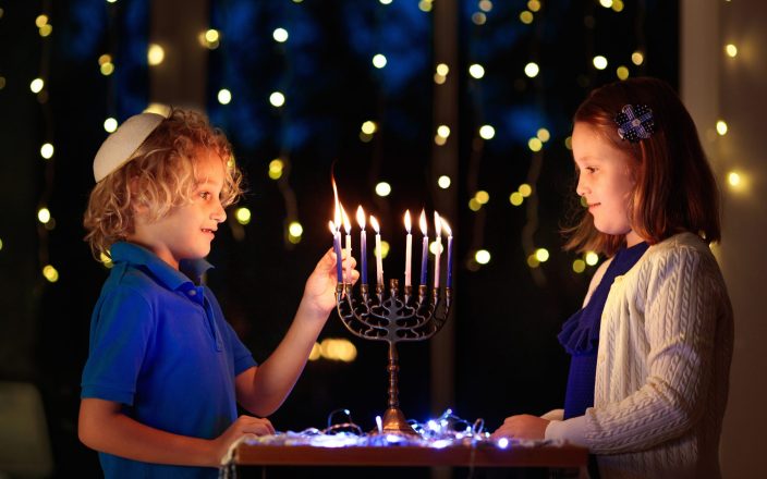 young boy and girl lighting hannukah candles