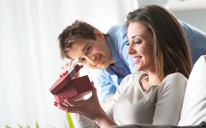 woman opening christmas gift from husband smiling