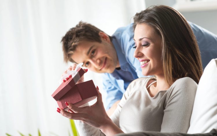 woman opening christmas gift from husband smiling