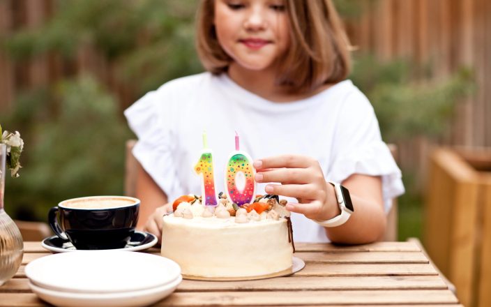 Girl putting candles on birthday cake