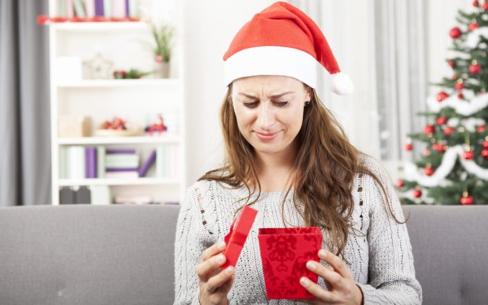 confused woman opening odd christmas gift