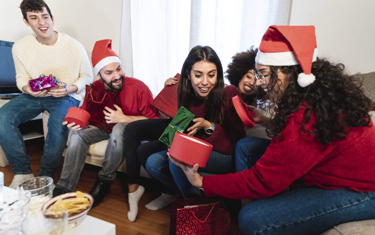 Friends sharing gifts and laughter in a cozy Christmas gathering