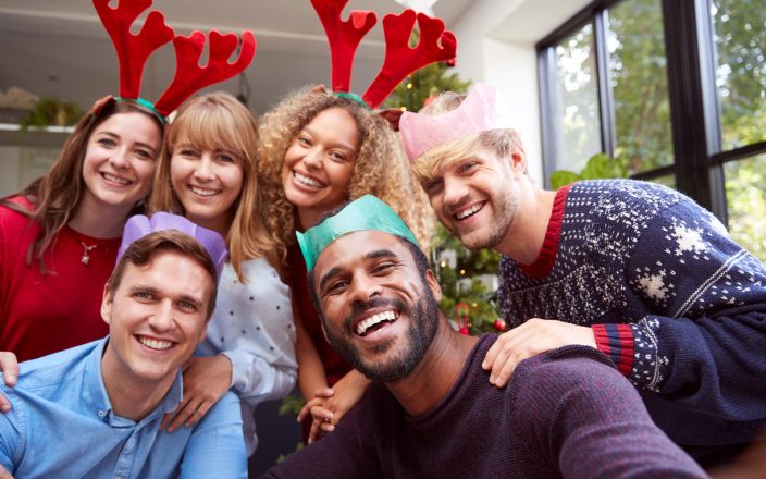 Retro Style Shot Of Group Of Friends Enjoying Christmas Party At Home Together Taking Selfie