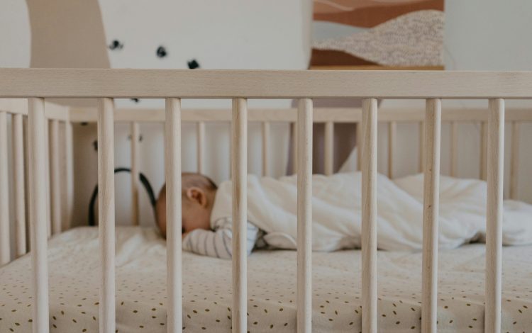 Baby sleeping in a crib with a soft mattress and cozy blanket, representing a peaceful scene ideal for parents using the best baby monitor.