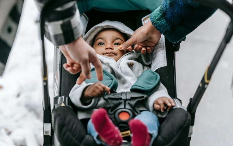 A baby is watched by his parents while being taken for a walk in one of the top baby strollers of 2024.