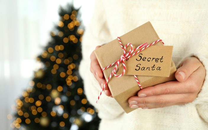 Woman holds Secret Santa gift box, close up